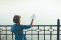 Girl launching toy paper airplane looking to lake
