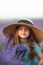 Girl lavender field in a blue dress with flowing hair in a hat stands in a lilac lavender field