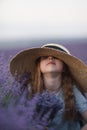 Girl lavender field in a blue dress with flowing hair in a hat stands in a lilac lavender field Royalty Free Stock Photo