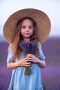Girl lavender field in a blue dress with flowing hair in a hat stands in a lilac lavender field