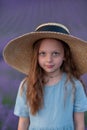 Girl lavender field in a blue dress with flowing hair in a hat stands in a lilac lavender field Royalty Free Stock Photo