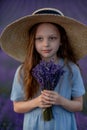 Girl lavender field in a blue dress with flowing hair in a hat stands in a lilac lavender field Royalty Free Stock Photo