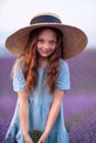 Girl lavender field. Laughing girl in a blue dress with flowing hair in a hat stands in a lilac lavender field Royalty Free Stock Photo