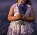 girl lavender field in a pink dress holds a bouquet of lavender on a lilac field. Aromatherapy concept, lavender oil