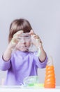 A girl in a lavender long sleeve stretches an green slime spiderweb with her hands