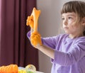 A girl in a lavender long sleeve stretches an orange slime with her hands