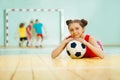 Girl laying on the floor of sports hall with ball Royalty Free Stock Photo