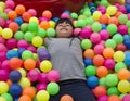 Girl lays on the big heap of multicolored small balls.