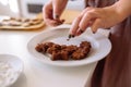 Girl lays out homemade finished chocolate chip cookies on a white plate.