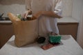 The girl lays out the products from the bag on the table. A close-up of the girl pulls groceries out of a paper bag