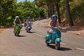 Girl leads a group of bikers riding a vintage italian scooter Vespa