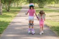 Girl leads her older sister, who is learning to rollerblade, by holding her hand