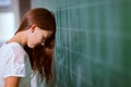 Girl leaned her head on the blackboard