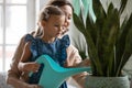 Girl learning taking care of domestic green plants from grandmother.