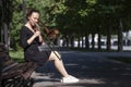 Girl learning to play trombone. Girl plays sitting on a park bench