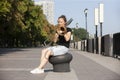 Girl learning to play trombone. Girl plays sitting on the promenade