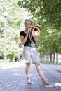 Girl learning to play trombone. Girl plays standing on the alley of a city park