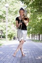 Girl learning to play trombone. Girl plays standing on the alley of a city park