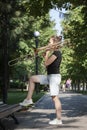 Girl learning to play trombone. Girl plays standing on the alley of a city park