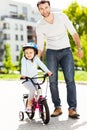 Girl learning to ride a bike with her father Royalty Free Stock Photo
