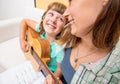 Girl learns to play guitar with support from his mother at home