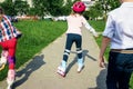 The girl learns to skate on the street. Children wear protective pads and a protective helmet for safe riding on rollers. Active