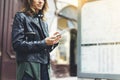 Girl in leather jacket holding smart phone on background map light box in sun atmospheric city, hipster using in female hands Royalty Free Stock Photo