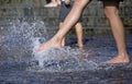 Girl leg playing with fountain water jets at the square Royalty Free Stock Photo