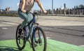 Girl in leggings rides a bicycle with a backpack behind her while riding a green bike path at the Tilikum Crossing Bridge in Royalty Free Stock Photo