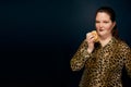 girl in a leopard blouse and with big earrings with a hamburger in her hand.