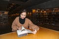 Girl in library turns page of book with smile Royalty Free Stock Photo