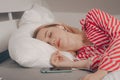 The girl lies on the bed with closed eyes asleep. Woman with headphones and phone, listening to soothing music before bed,