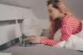 The girl lies on the bed with a laptop. Work from home, laziness. The girl is typing something on the Internet, freelance Royalty Free Stock Photo