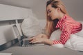 The girl lies on the bed with a laptop. Work from home, laziness. The girl is typing something on the Internet, freelance Royalty Free Stock Photo