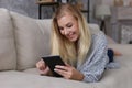 The girl lies on the couch and reads a tablet. Comfortably working remotely at home. Copy space Royalty Free Stock Photo