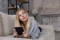 The girl lies on the couch and reads a tablet. Comfortably working remotely at home. Copy space Royalty Free Stock Photo