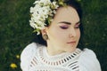 The girl lies on the grass in the park. Beautiful pink makeup on a girl. Brunette bride in a beautiful boho dress, with flowers