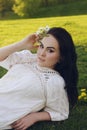 The girl lies on the grass in the park. Beautiful pink makeup on a girl. Brunette bride in a beautiful boho dress Royalty Free Stock Photo