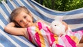 The girl lies on a hammock in the company of her pet, a white rabbit. A fluffy decorative bunny lies in the hands of a child. Pet