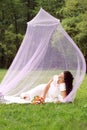 The girl lies in a pink summer airy tent on a lawn Royalty Free Stock Photo