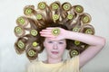 The girl lies with slices of kiwi in her loose hair and holds the kiwi in her palm. Close-up