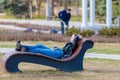 The girl lies on a sun lounger in the park with her eyes closed, hands behind her head. The girl is resting and relaxing