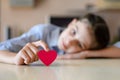 A girl lies on a table and holds a pink heart with her finger. Royalty Free Stock Photo
