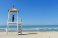 A girl on the lifeguard hut with the arms raised