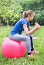 Girl lifting dumbbells on fitness ball Royalty Free Stock Photo