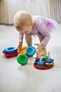 girl lifts pyramid rings from white pod in living room. Montessori wooden toy folded pyramid. Circle, quadra, triangle, rectangle
