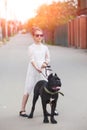 Girl In A Light Dress Poses And Holds A Large Black Dog Cane-corso