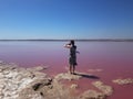 A girl in a light dress and silk scarf photographs a pink lake. Torrevieja, Spain. Royalty Free Stock Photo