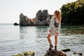 Girl in the light dress standing on the rock on the sea Royalty Free Stock Photo