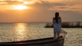 A girl stands in a boat and basks in the sunset. Text space
